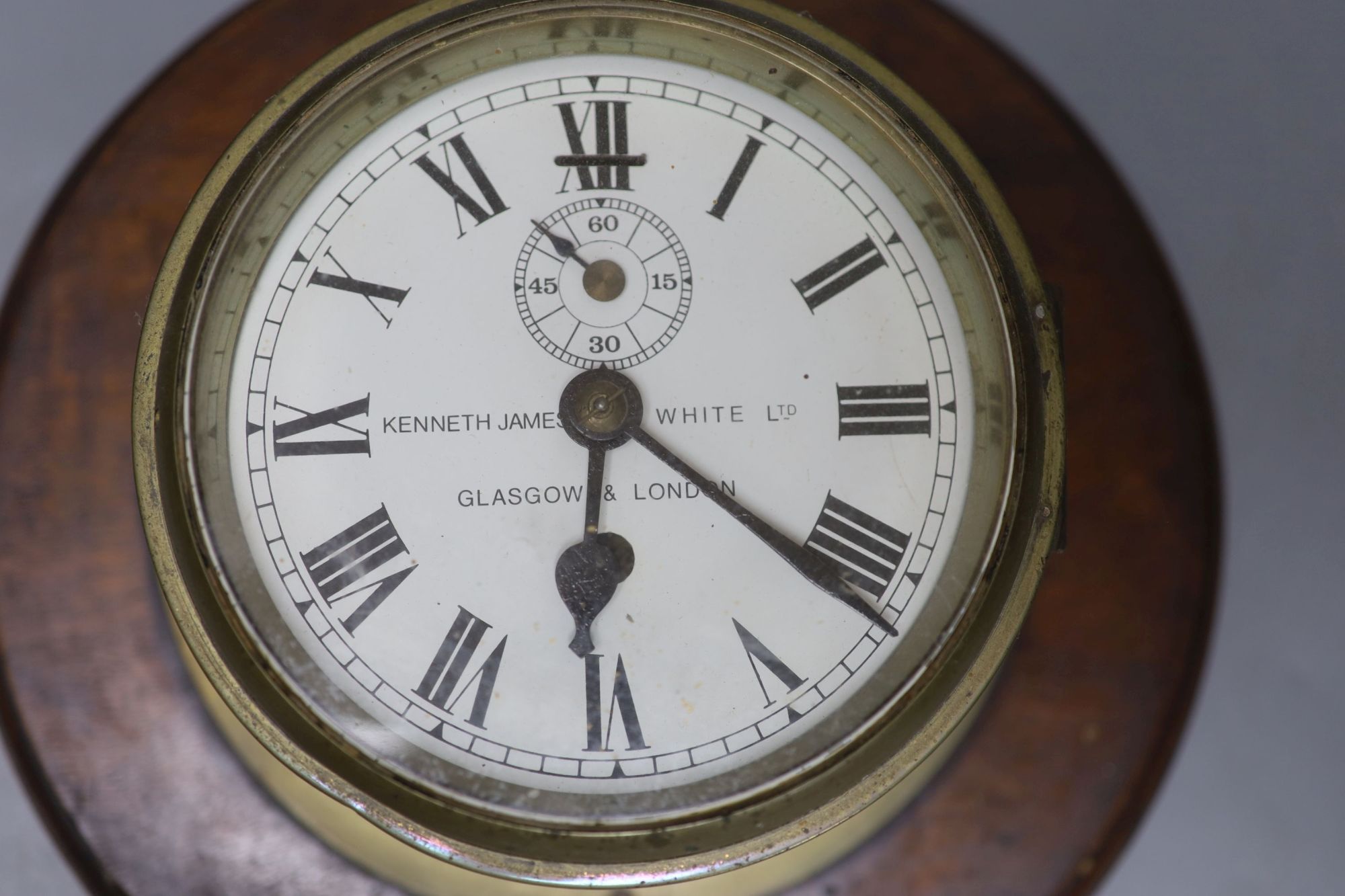 Kenneth James White Ltd., Glasgow and London. A brass cased bulkhead timepiece, mahogany mounted